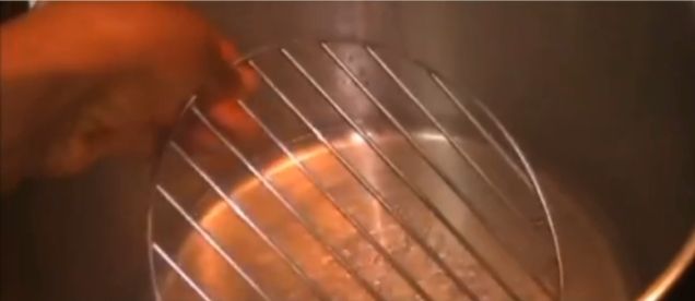 Step 5.2: When the water in the pot starts boiling, add a base to support the wraps (you can use the Uma leaf stalks or a stainless-steel base)