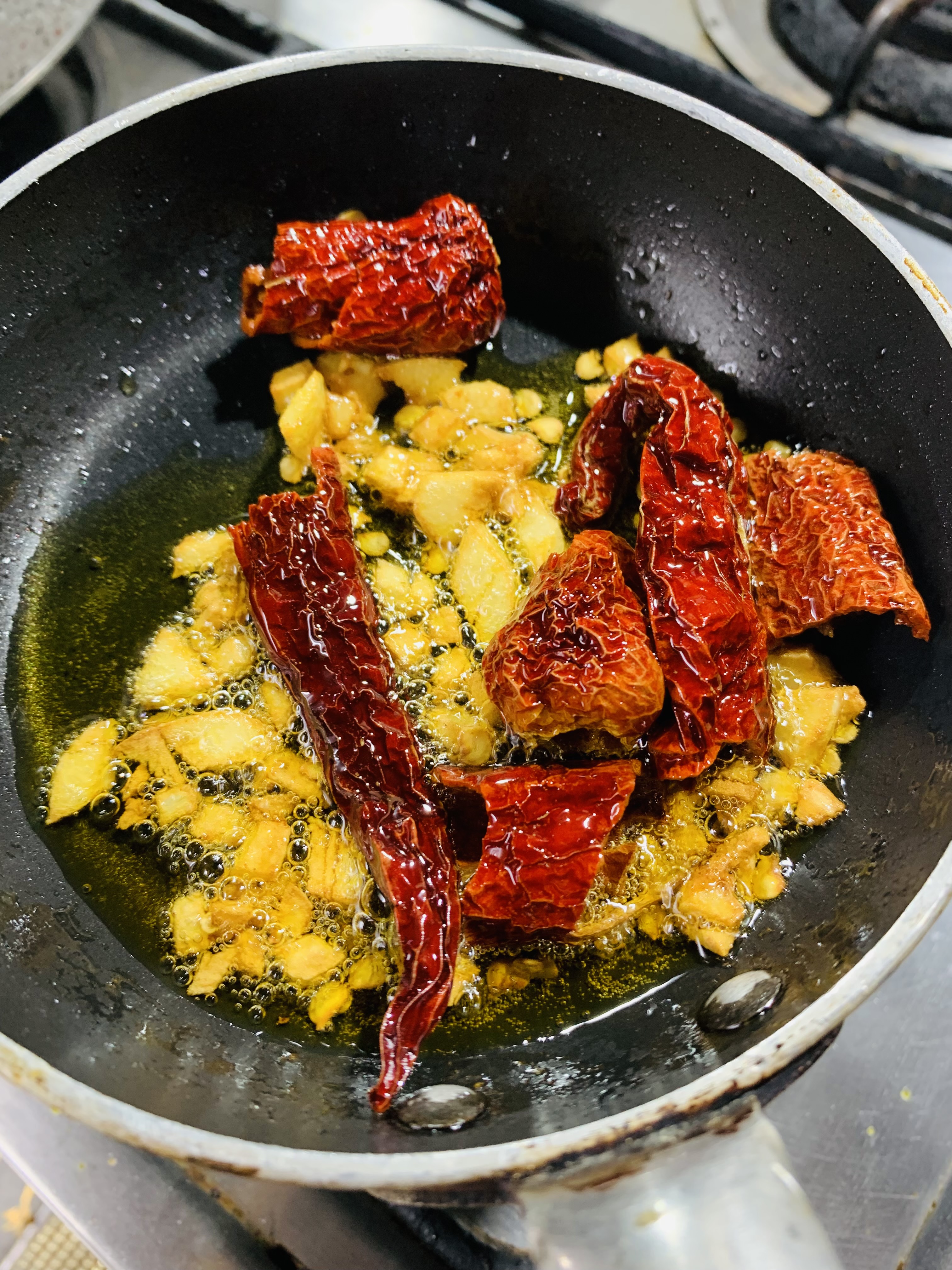 Step 5.1: Add dried red chillies, stir briefly, and immediately pour the tempering over the palak chicken
