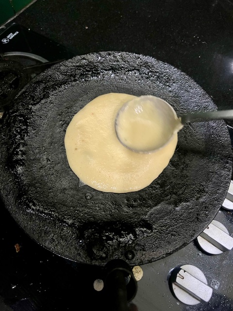 Step 3.1: Pour a ladleful of batter onto the hot tawa