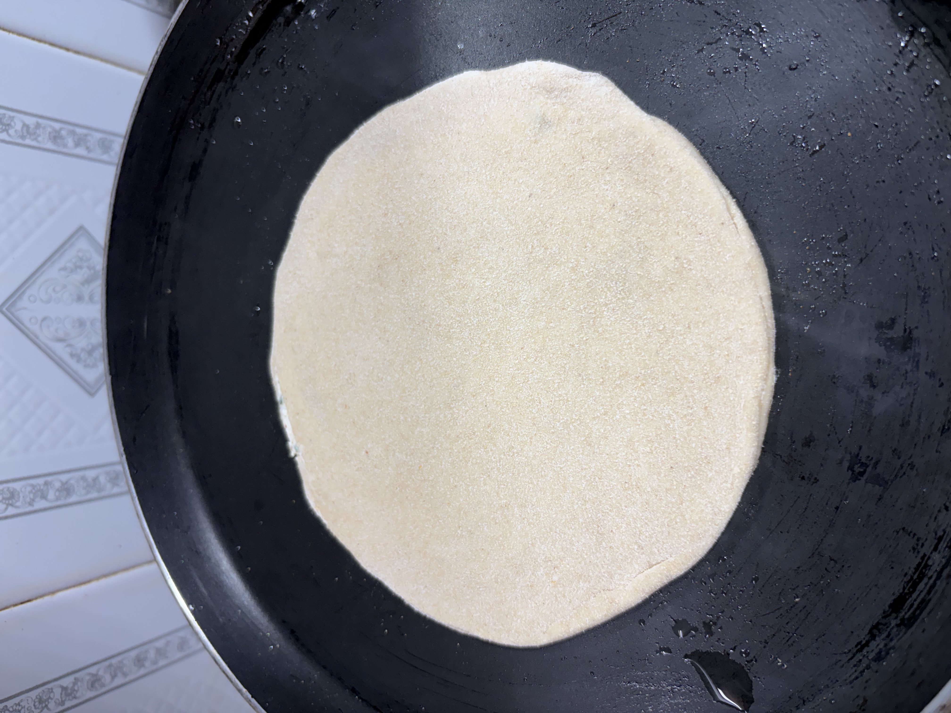 Step 5.1: Place the paratha on the hot tawa and cook until small brown spots appear