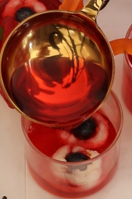Step 1.1: Pour the jelly mixture into the glasses, filling them halfway and covering the lychees