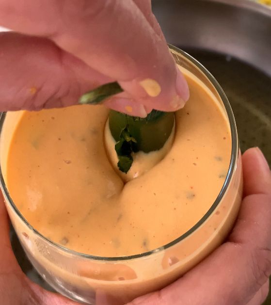 Step 2.1: Dip each stuffed chilli pepper into the gram flour batter, then carefully place them into the hot oil