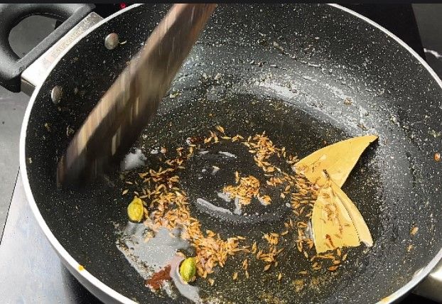 Step 2.6: In a large kadai, heat oil and sauté cumin, cinnamon, cardamom pods, and bay leaf