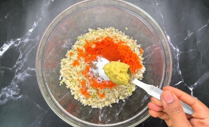 Step 1.6: In a large bowl, combine finely chopped cabbage, grated carrot, chili powder, pepper powder, salt, and ginger garlic paste