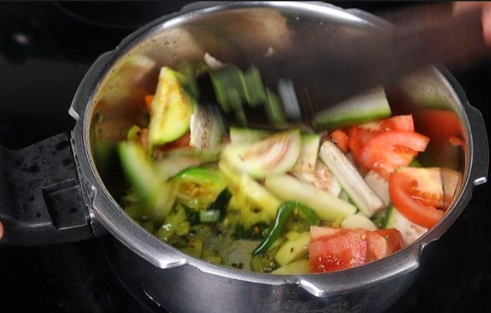 Step 3.6: Add the chopped brinjal, potato, bottle gourd, carrot, tomato slices, and salt Stir fry for a few minutes