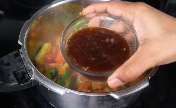 Step 3.1: Pour in the tamarind extract, cover with a lid, and cook for 2 minutes on low flame