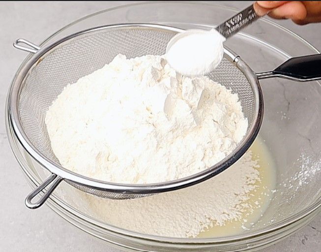 Step 1.3: Place a sieve over the bowl and add all-purpose flour, baking powder, baking soda, and salt