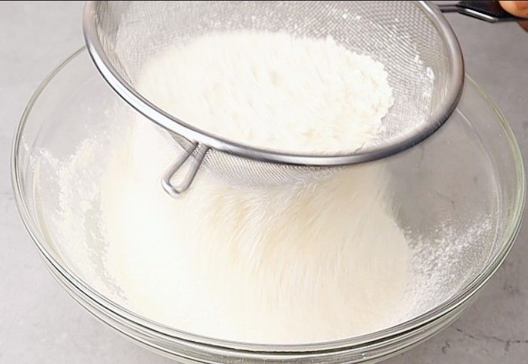 Step 1.6: Place a sieve over the bowl and add all-purpose flour, baking powder, baking soda, and salt