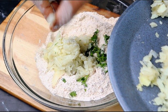 Step 2.2: Add the mashed potatoes and chopped coriander leaves to the flour mixture and mix thoroughly