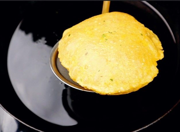 Step 3.1: Slide the prepared pooris into the hot oil and deep fry them, flipping once, until golden brown