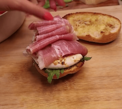 Step 2.1: Layer on arugula, burrata, tomatoes, prosciutto, and top it all off with fresh basil and a balsamic glaze drizzle