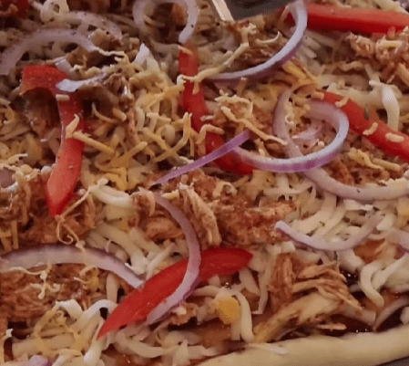 Step 1.3: Spread BBQ sauce over the par-baked dough, then layer with mozzarella cheese, shredded chicken, red onions, and red bell peppers