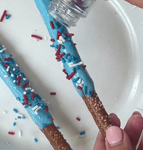 Step 1.3: Sprinkle the coated pretzels with patriotic sprinkles and drizzle additional melted candy for decoration