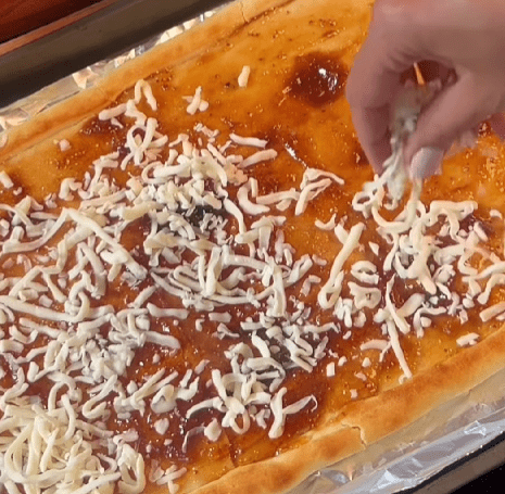 Step 1.2: Spread fig jam over the parbaked dough, then top with shredded mozzarella and thinly sliced red onion