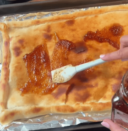 Step 1.1: Spread fig jam over the parbaked dough, then top with shredded mozzarella and thinly sliced red onion
