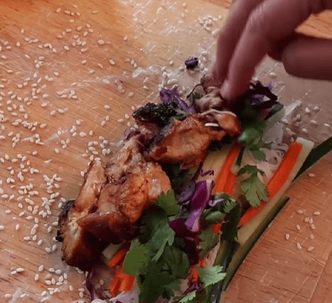 Step 4.1: Layer noodles, veggies, and herbs just off the center of the rice paper, then add chicken