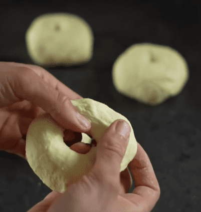 Step 1.1: Use your finger to poke a hole in the center of each ball, then gently stretch the hole to shape the dough into a bagel
