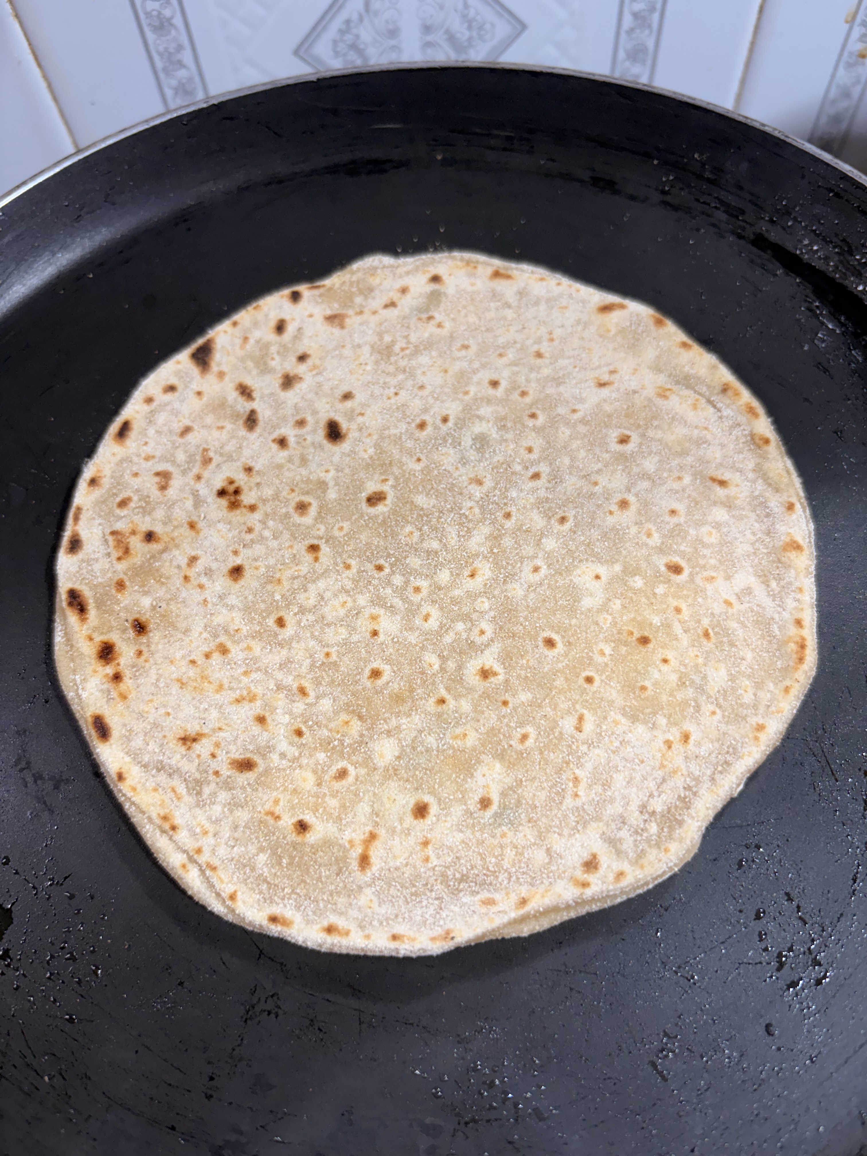 Step 5.2: Place the paratha on the hot tawa and cook until small brown spots appear