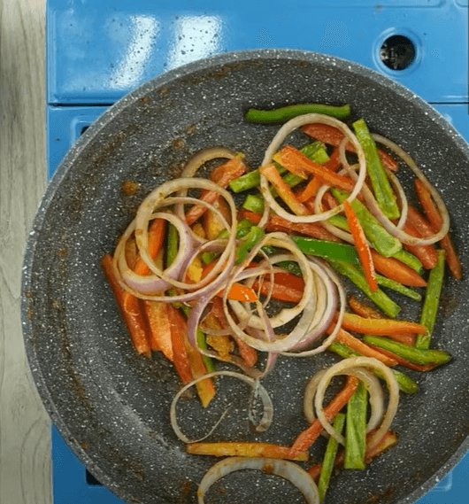 Step 1.1: In the same frying pan, add cooking oil, onion rings, tomato, and capsicum