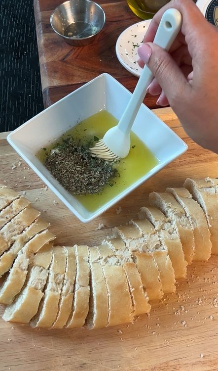 Step 2.1: While the tomatoes bake, slice the baguette and spread with garlic butter made from butter, garlic, salt, seasonings, and parmesan