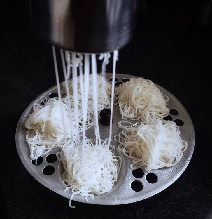 Step 1.1: Grease the steamer plate, then press the dough through the idiyappam presser onto the steamer plate