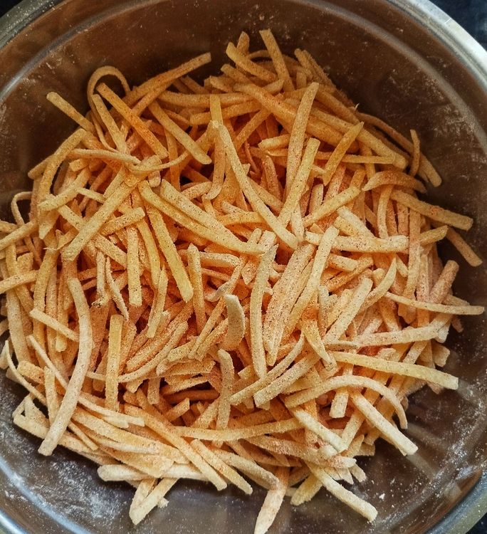 Step 1.1: Add the dried potato sticks to the bowl with the prepared corn flour mix and mix well