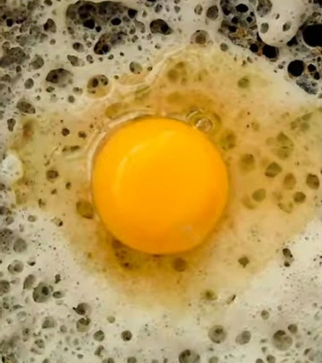 Step 1.1: Crack open an egg in the center of the appam and gently tilt the pan again