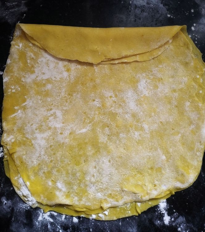 Step 2.1: Start rolling the layered sheets from one side into a log shape