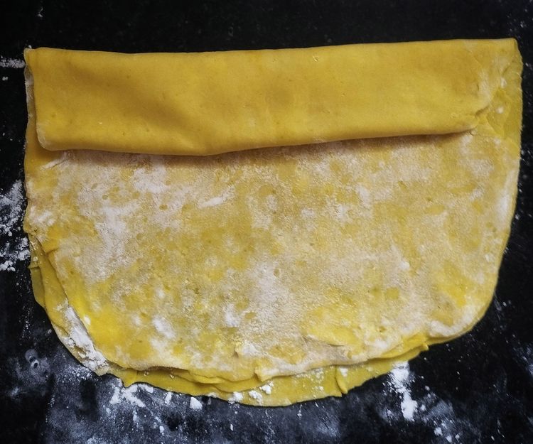 Step 2.2: Start rolling the layered sheets from one side into a log shape