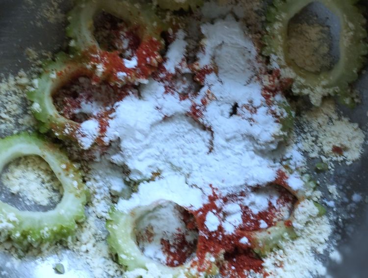 Step 1.1: Add chili powder, turmeric powder, amchur powder, garam masala powder, salt, chickpea flour, and corn flour to the rinsed bitter gourd slices