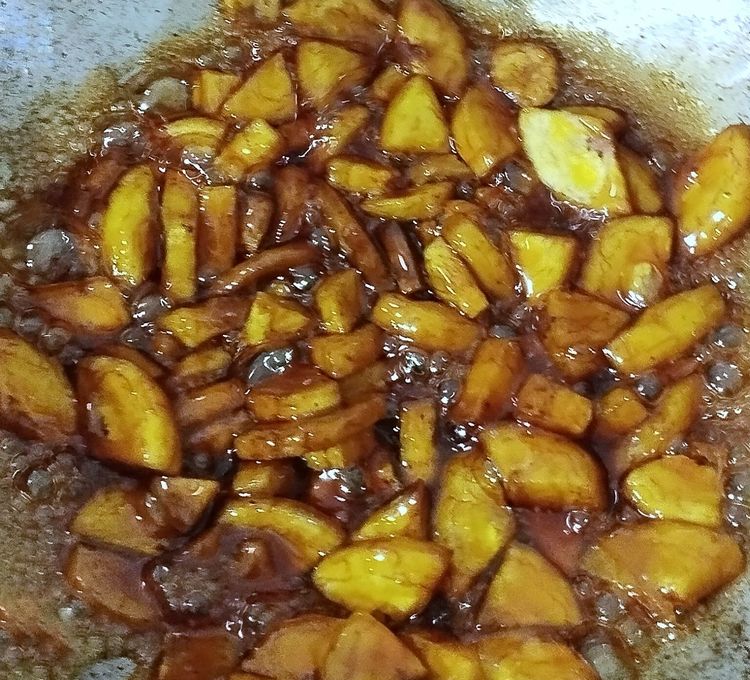 Step 1.1: Drop the fried banana chips into the jaggery syrup and stir continuously until the syrup thickens and coats the chips well