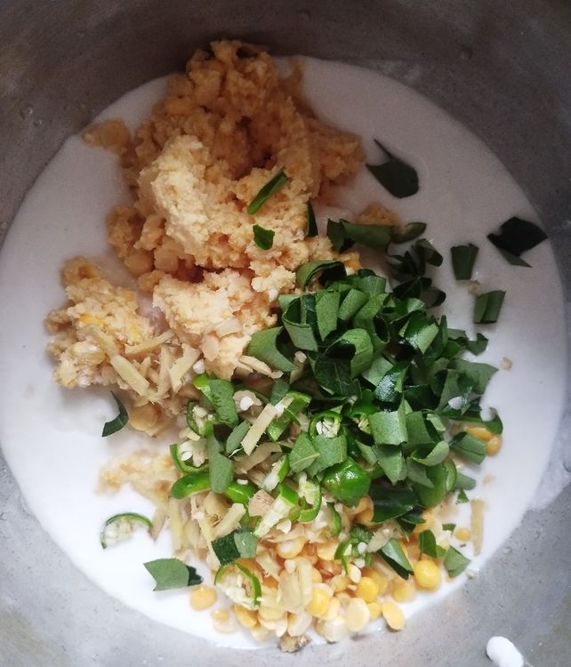 Step 3.1: Add reserved soaked whole peas parippu, chopped ginger, chopped green chilli, chopped curry leaves, asafoetida powder, baking soda, and salt to the ground mixture