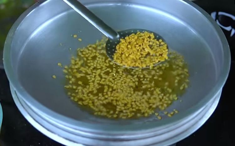 Step 2.3: Take a perforated ladle, place it on the hot oil, pour the batter over the ladle, and gently spread it using a spoon so that it drops into the hot oil