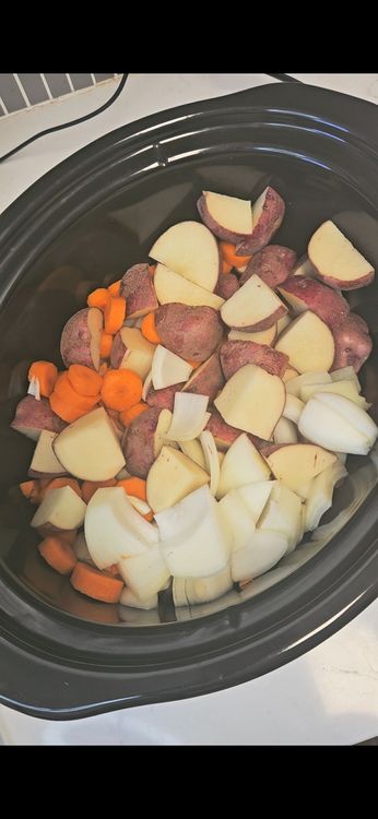 Step 3.1: Place quartered potatoes, carrot chunks, smashed garlic, and onion quarters at the bottom of the slow cooker