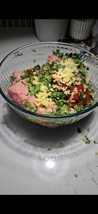 Step 2.1: In the bowl with the cooked onion and garlic, add ground turkey, soy sauce, chicken bone broth, cilantro, grated ginger, fermented chili paste, siracha, and msg