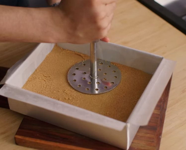 Step 5.2: Transfer into the lined tin and press firmly using a potato masher