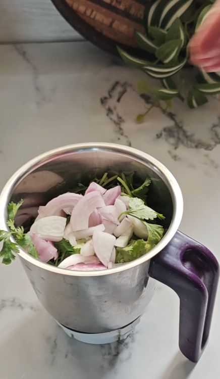 Step 1.1: Add chopped onion and green coriander leaves with stems to the mixer jar