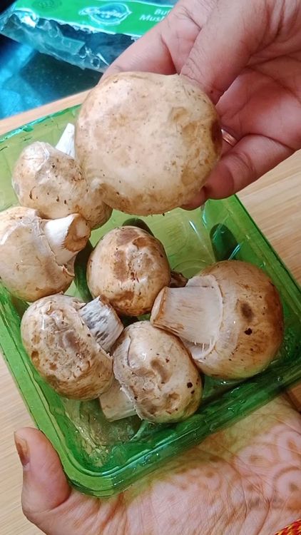 Step 1.1: Cut open the button mushroom packet and transfer the mushrooms to a large bowl filled with water