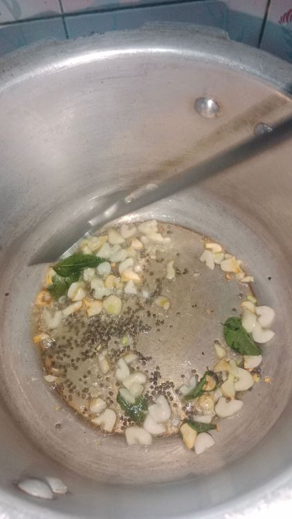 Step 2.2: Heat oil in a pressure cooker and temper mustard seeds, curry leaves, and chopped garlic pods