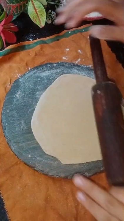 Step 2.2: Roll this triangular piece gently into a thin triangular chapati using dry flour