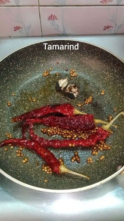 Step 2.1: In a pan, heat 1 tsp coconut oil and fry 1 tsp coriander seeds, 3-4 Kashmiri dry red chillies, and 1 small piece of tamarind for a minute