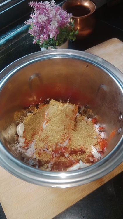 Step 1.1: Add the boiled tomato cubes to a mixie jar along with shredded coconut, turmeric powder, Kashmiri red chilli powder, coriander powder, rock salt, tamarind, and garlic pods