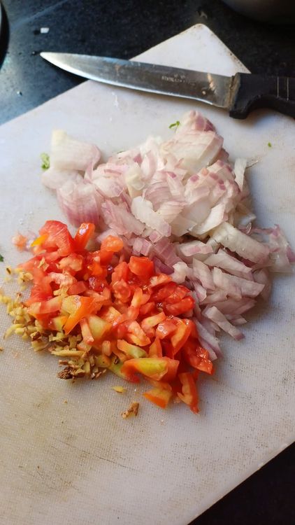 Step 1.1: In the same pan, heat groundnut oil and add finely chopped onion, tomato, green chillies, crushed garlic, and finely chopped ginger