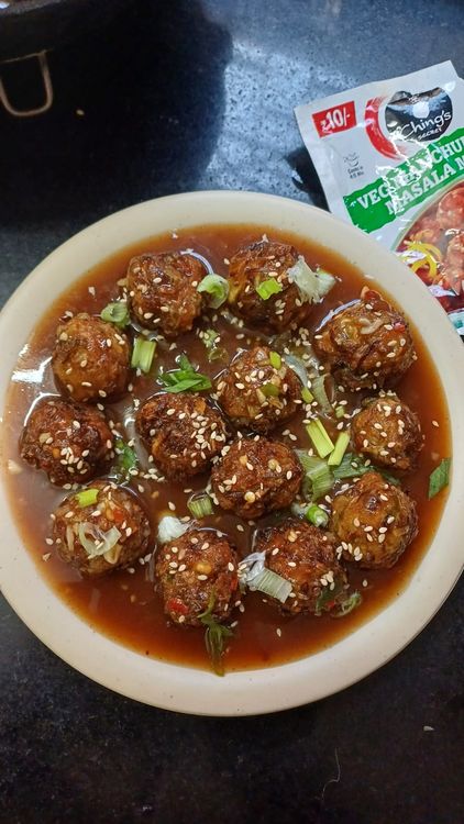Step 3.1: Plate the Manchurian gravy, then garnish with chopped coriander leaves, sesame seeds, and spring onion