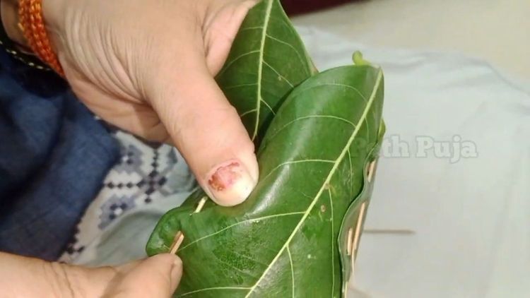 Step 2.2: Take 4 leaves, place them one over the other like a star as shown below in the photo, Fold into small cups (khotte) and stitch with thin bamboo sticks or toothpicks
