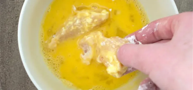 Step 1.1: Place the floured chicken tenders in the egg mixture, ensuring to remove excess egg before proceeding