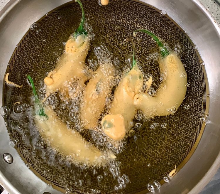 Step 2.2: Dip each stuffed chilli pepper into the gram flour batter, then carefully place them into the hot oil