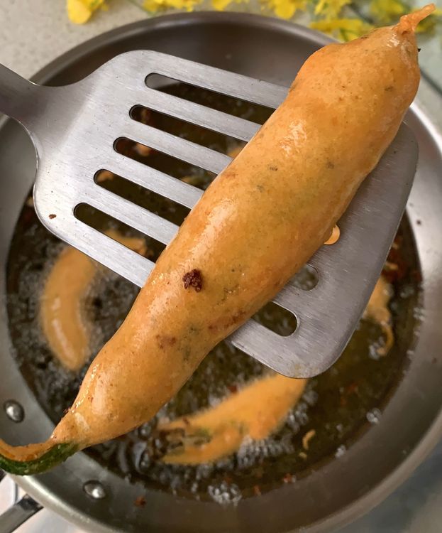 Step 2.3: Dip each stuffed chilli pepper into the gram flour batter, then carefully place them into the hot oil