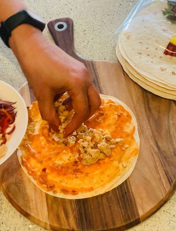 Step 1.1: Place some cooked chicken mince, capsicum, and carrots in the centre of the tortilla