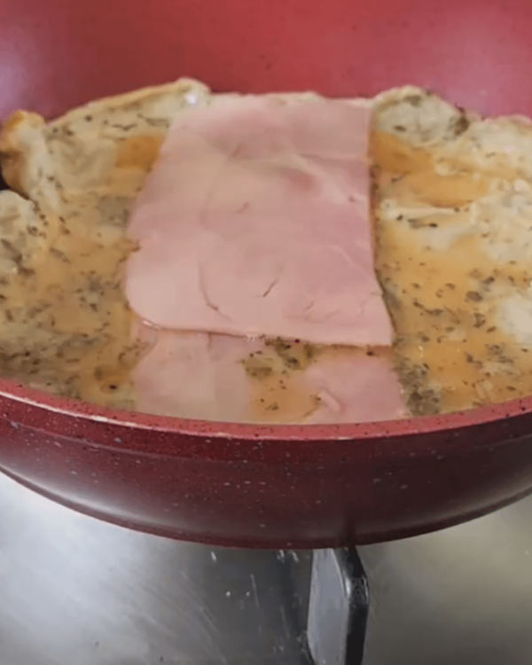 Step 2.1: As the egg starts to set, place two slices of ham on top